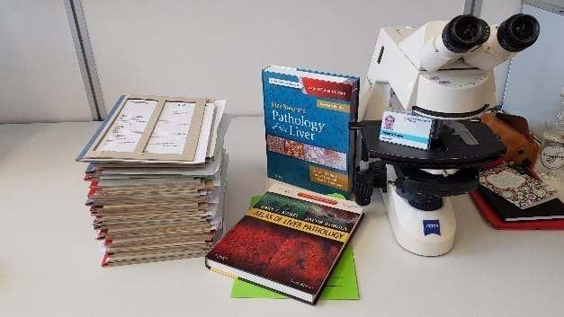Et bord med et mikroskop og b&#248;ker om patologi - Foto: privat